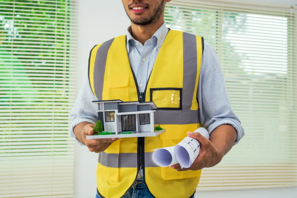 Builder holding house model and plans for residential construction.